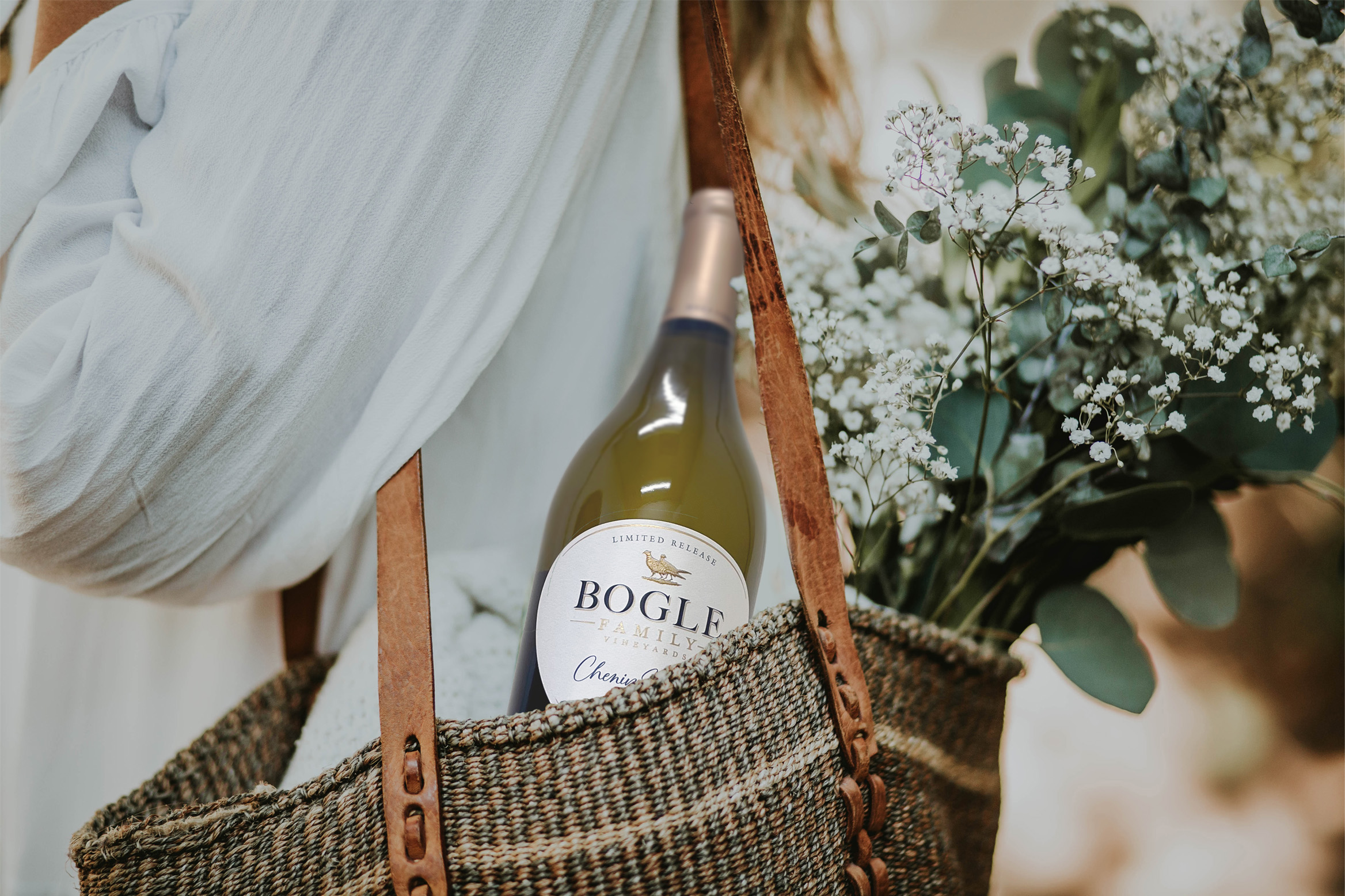 Woman holding bag with bottle of Bogle Chenin Blanc and flowers